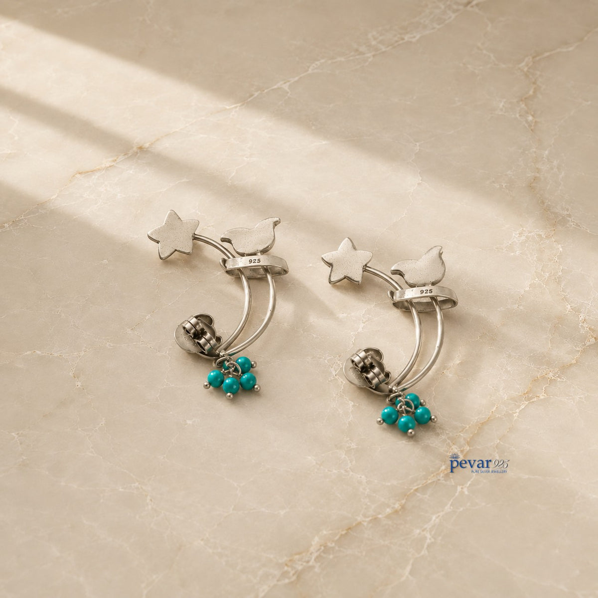 pevar925 oxidized 925 silver earrings featuring star and bird motifs with dangling turquoise beads on marble surface