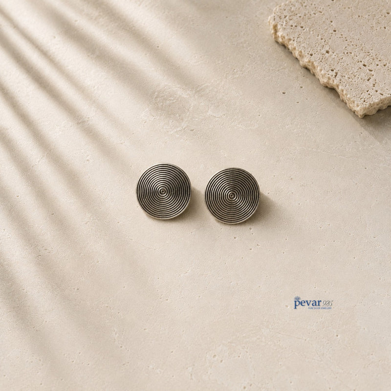 pevar925 oxidized 925 sterling silver disc stud earrings with concentric circle detailing on a textured stone surface