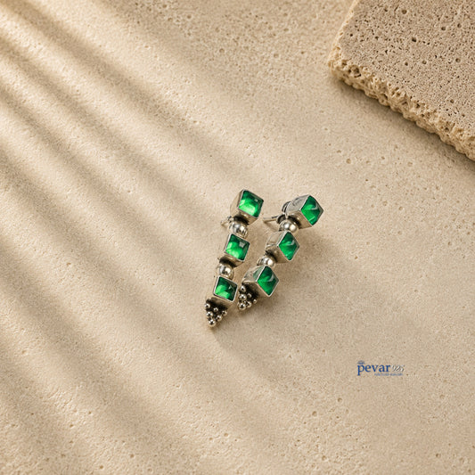 pevar925 oxidized 925 silver trio earrings featuring three square emerald green stones on a textured beige surface