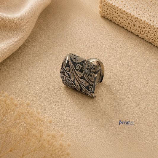 pevar925 oxidized silver adjustable ring with rectangular floral chitai engraving on a neutral textured background