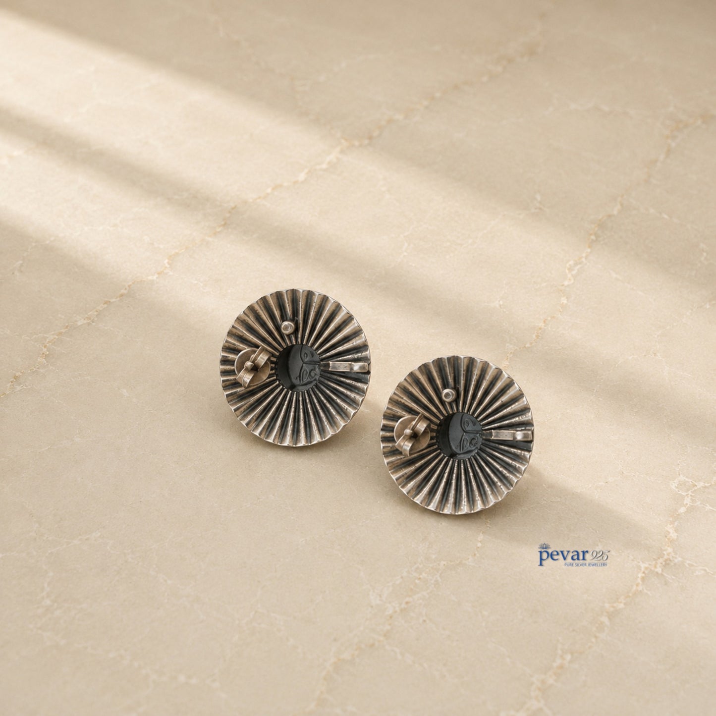 pevar925 oxidized silver temple goddess earrings with a circular ridged frame and golden motif on a neutral surface.