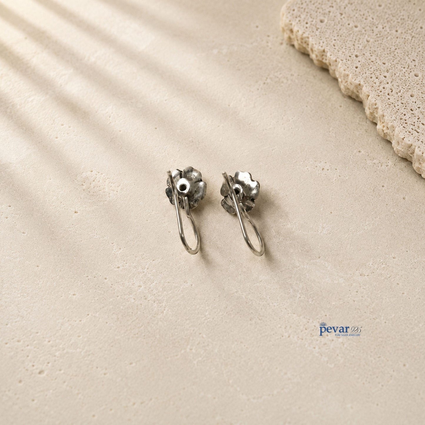 pevar925 oxidized 925 silver rose flower drop earrings with black stone accents on a textured beige surface