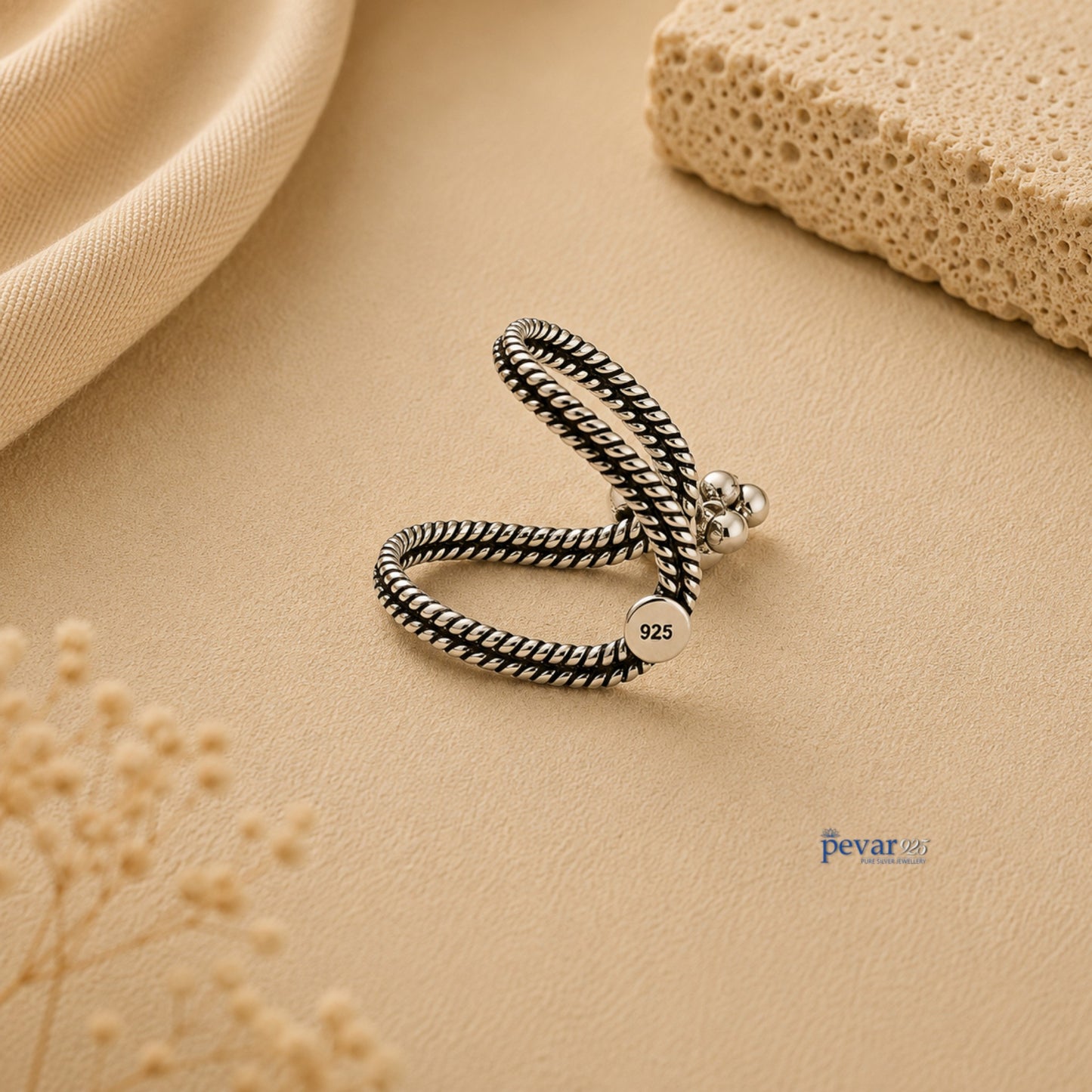 pevar925 oxidized silver V-shape ring with twisted band and ghunghroo accents on a neutral textured background