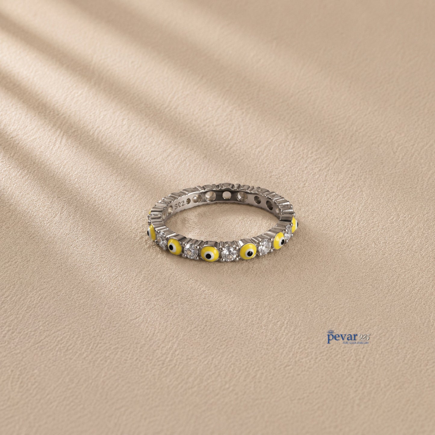 pevar925 sterling silver band ring featuring alternating yellow evil eye motifs and clear stones on a neutral background