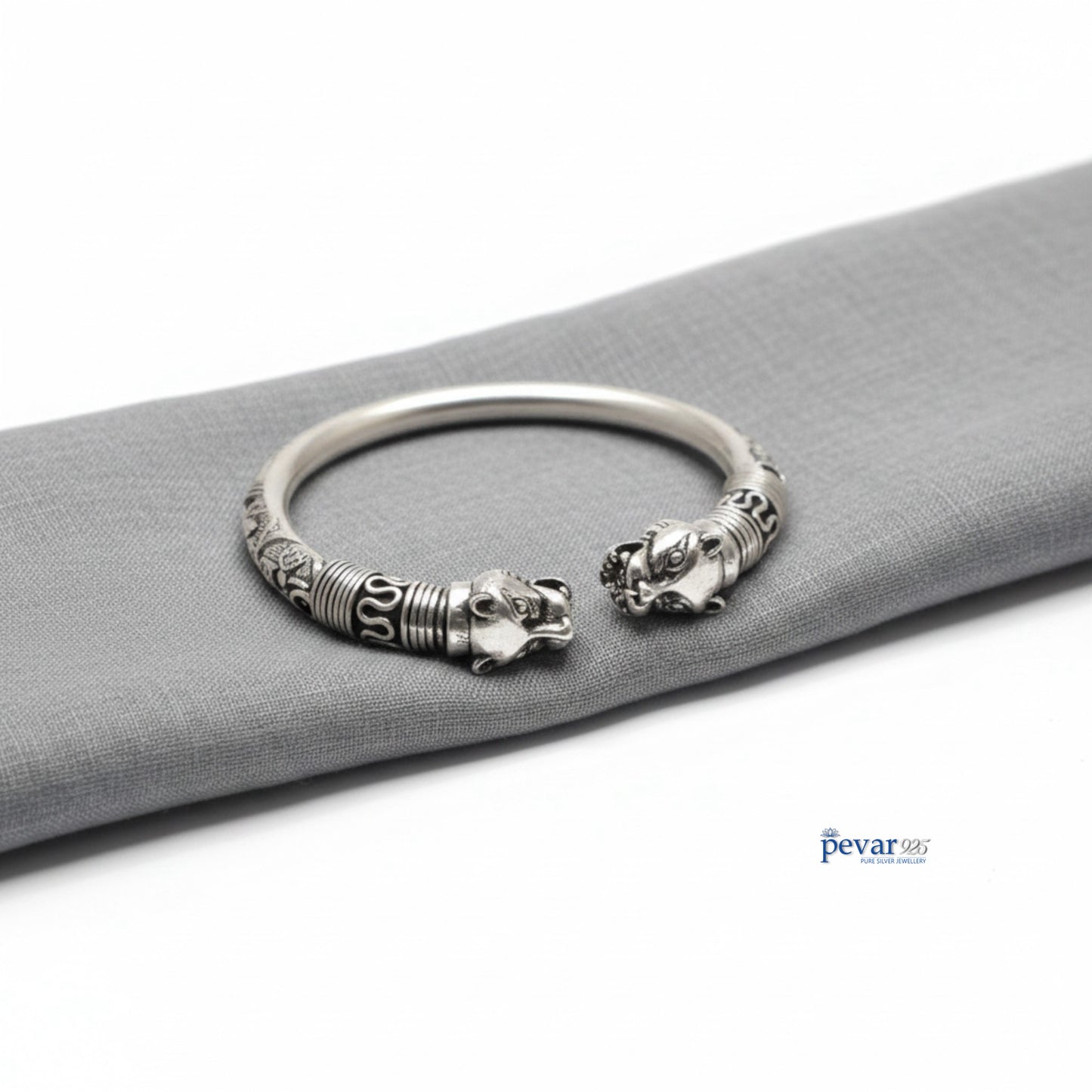 Silver bracelet with lion head designs on a gray surface