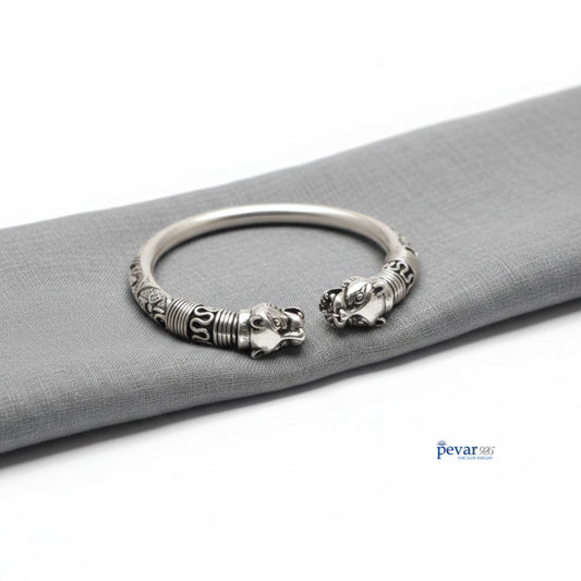 Silver bracelet with lion head designs on a gray surface
