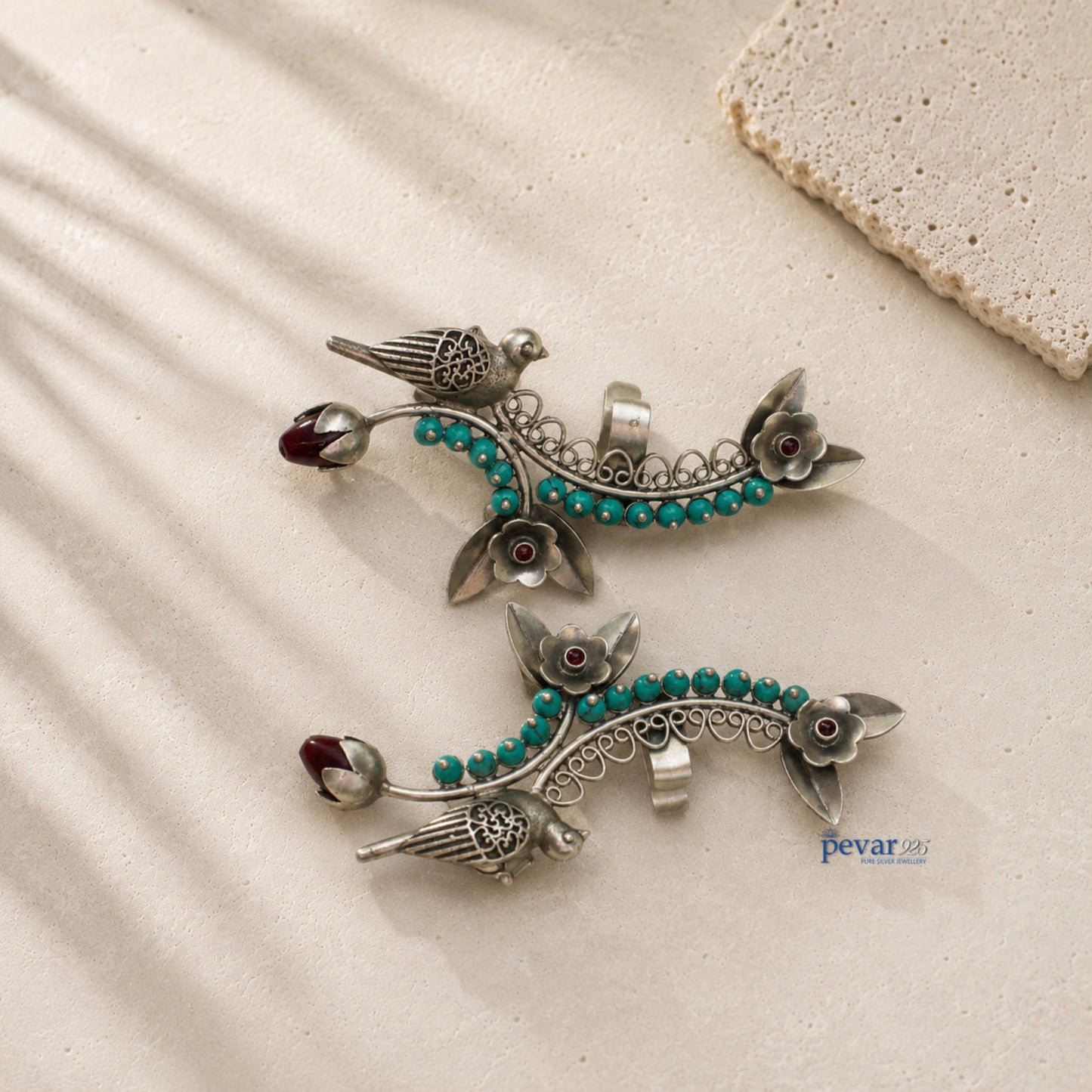 Pair of silver earrings with turquoise beads on a beige surface