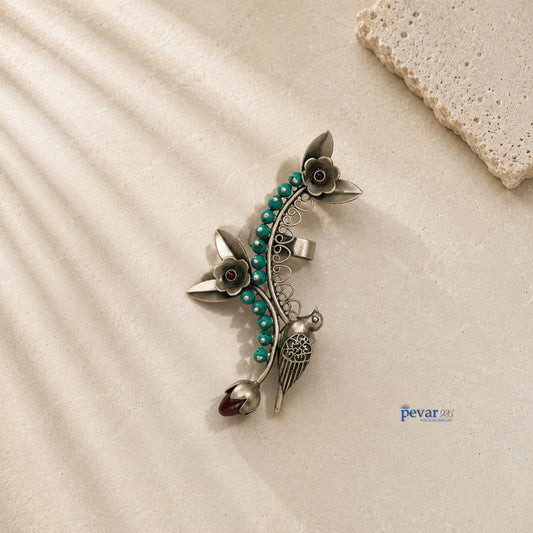 Decorative brooch with floral design and turquoise beads on a beige surface