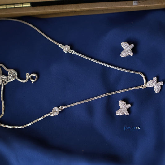 Silver butterfly-themed jewelry set on a blue fabric background