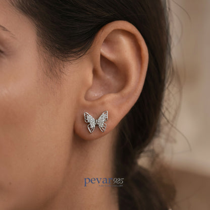 Butterfly-shaped earrings worn by a person, with 'pevar925' branding visible.