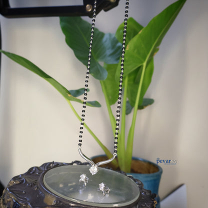 Silver necklace with a pendant on a decorative stand with a plant in the background