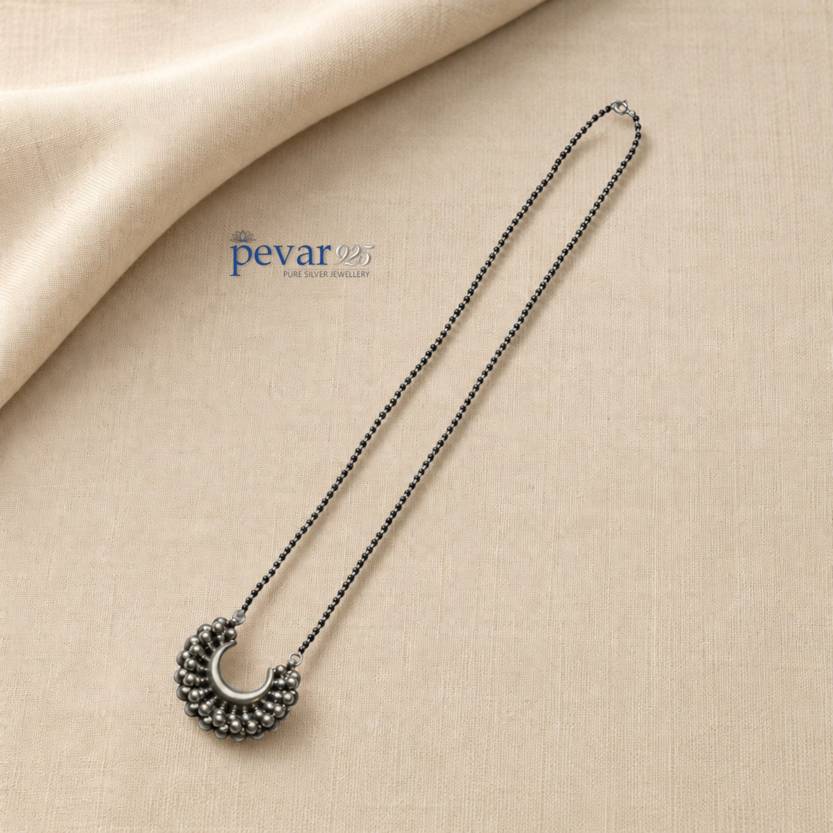 pevar925 oxidized 925 sterling silver mangalsutra with black beads and a crescent-shaped bead pendant on beige fabric.