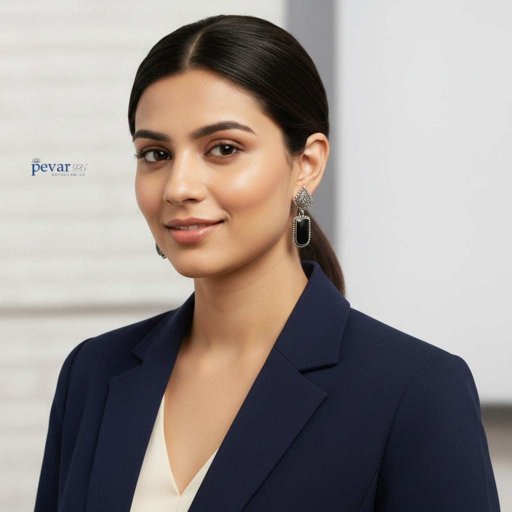 A woman wearing pevar925 oxidized sterling silver drop earrings featuring ornate frames and black stones.