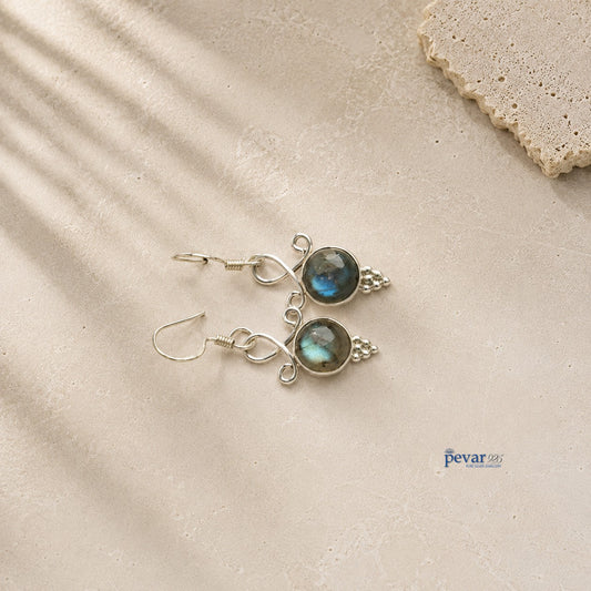 pevar925 oxidized 925 silver hook earrings featuring round blue crom stones on a textured beige stone background