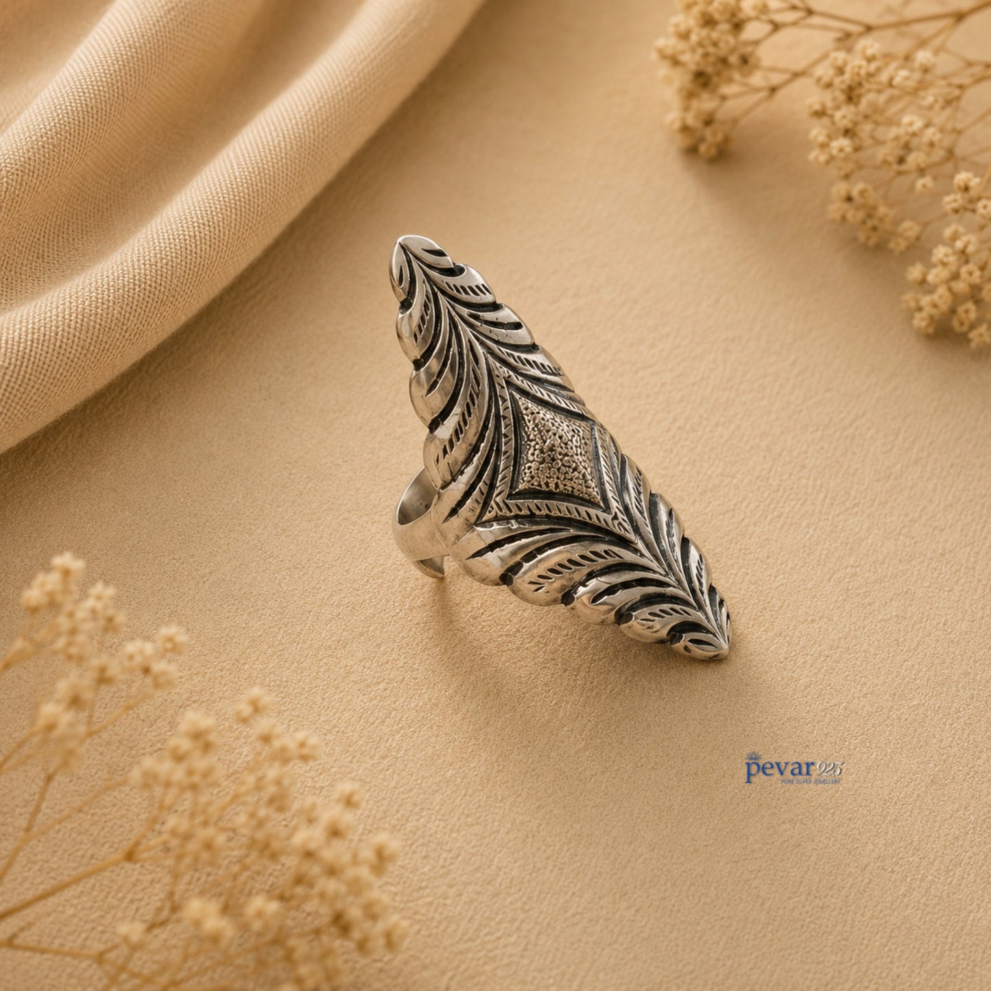pevar925 oxidized silver adjustable ring with intricate diamond motif and floral chitai engraving on beige fabric.
