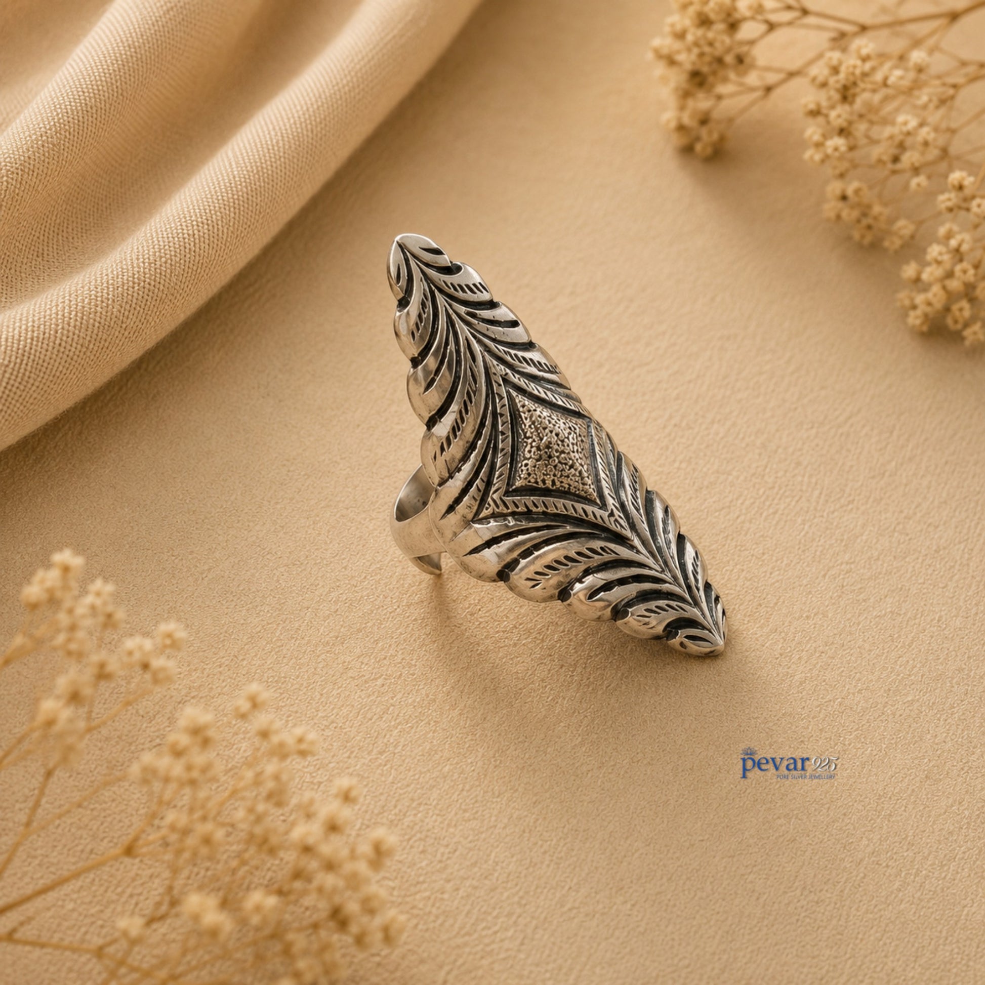 pevar925 oxidized silver adjustable ring with intricate diamond motif and floral chitai engraving on beige fabric.