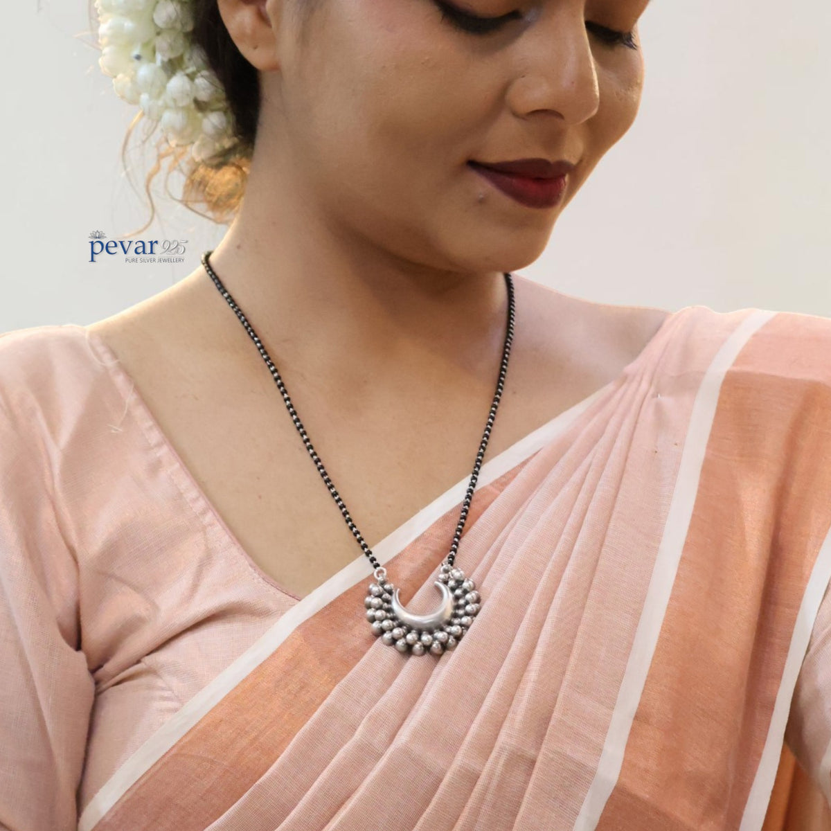 pevar925 oxidized sterling silver mangalsutra with black beads and a crescent pendant worn by a woman in a saree