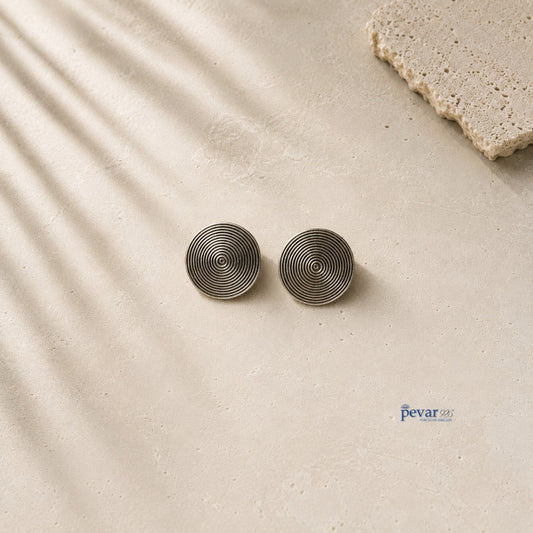 pevar925 oxidized 925 sterling silver disc stud earrings with concentric circle detailing on a textured stone surface
