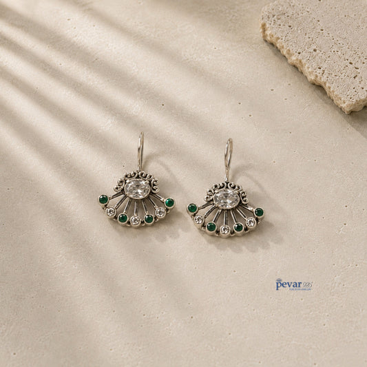 pevar925 oxidized 925 silver fan earrings with green stones and clear crystals on a textured stone surface