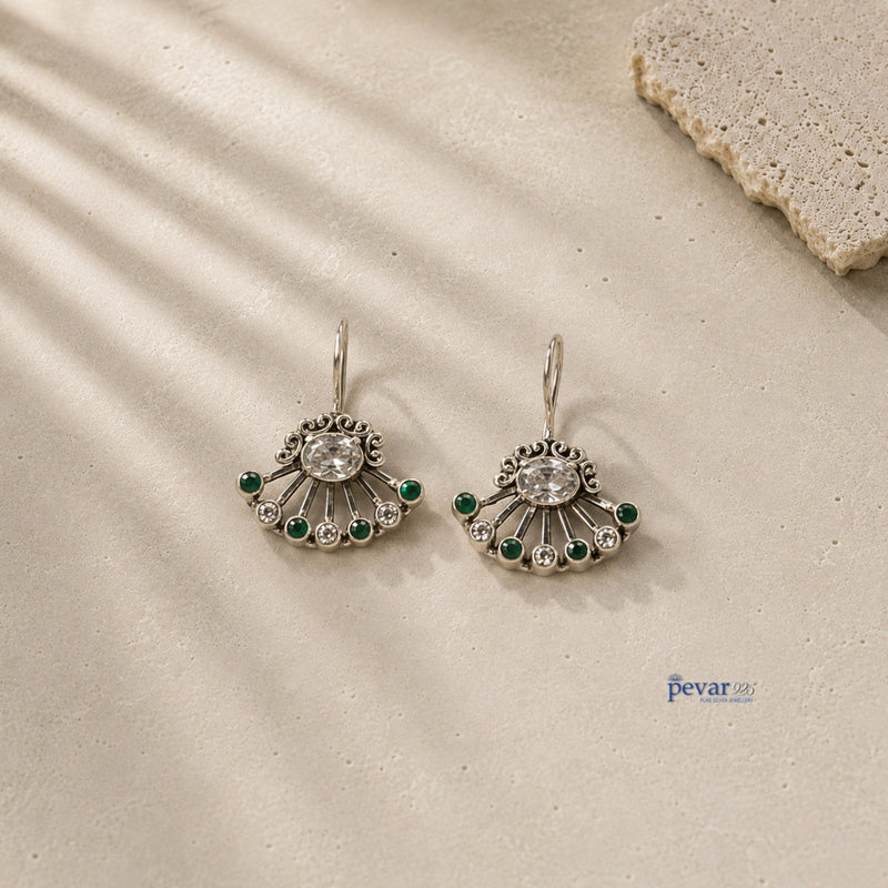 pevar925 oxidized 925 silver fan earrings with green stones and clear crystals on a textured stone surface