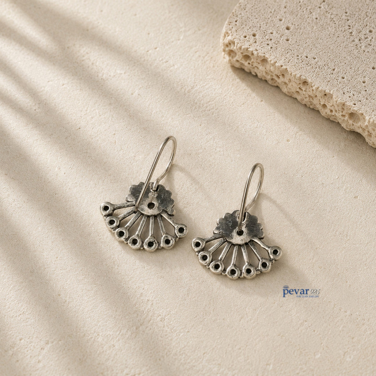 pevar925 oxidized 925 silver fan-shaped earrings with intricate detailing on a textured stone surface