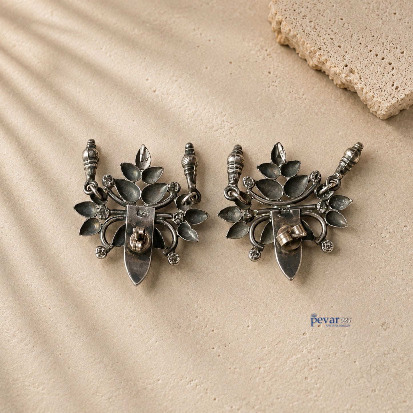 pevar925 oxidized 925 silver ear cuffs featuring large floral motifs with secure backings on a textured stone surface.