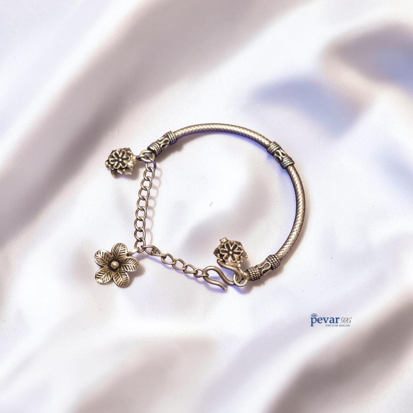 pevar925 oxidized 925 sterling silver kada bracelet with delicate floral charms on a white satin background