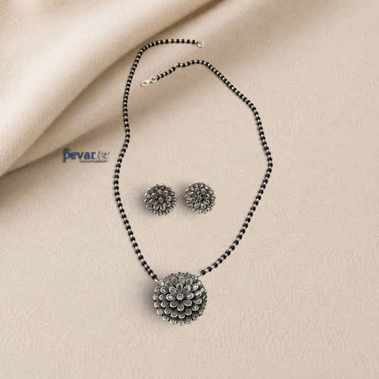 pevar925 oxidized silver mangalsutra set with floral glass charm pendant and matching stud earrings on beige fabric