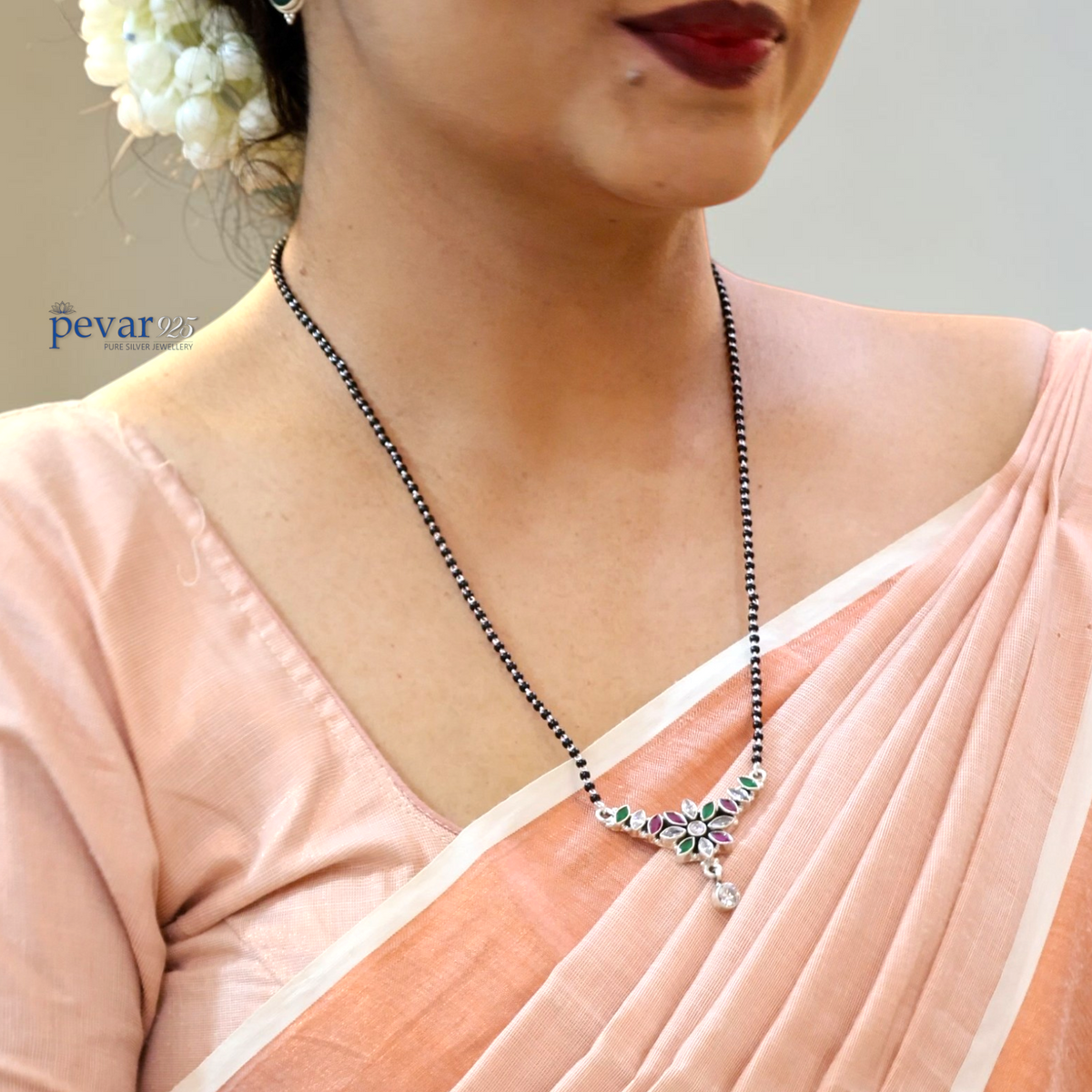 Woman wearing a pevar925 oxidized silver mangalsutra with maroon and green floral pendant and black bead chain