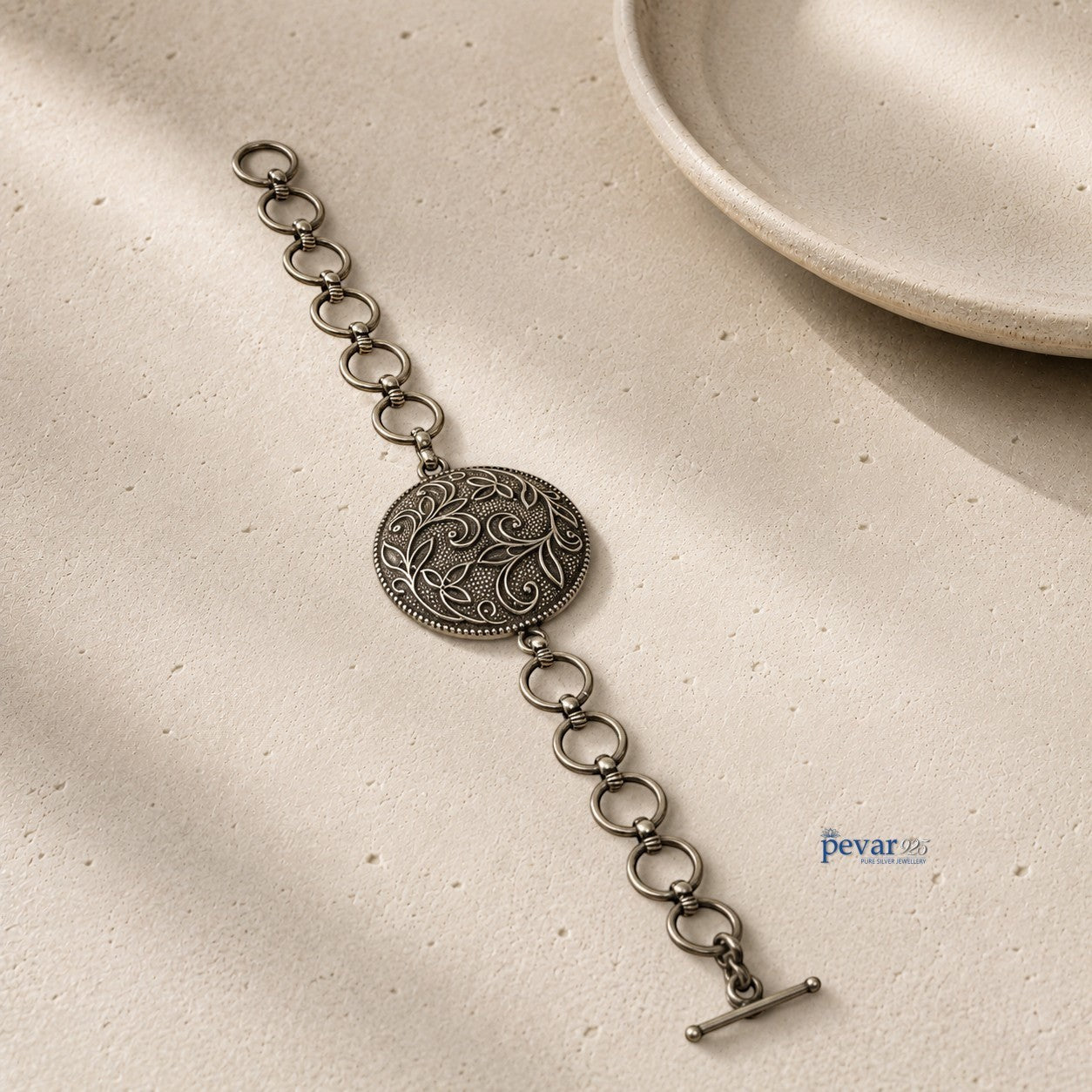 pevar925 oxidized 925 sterling silver bracelet featuring a round floral medallion with intricate vine engravings.