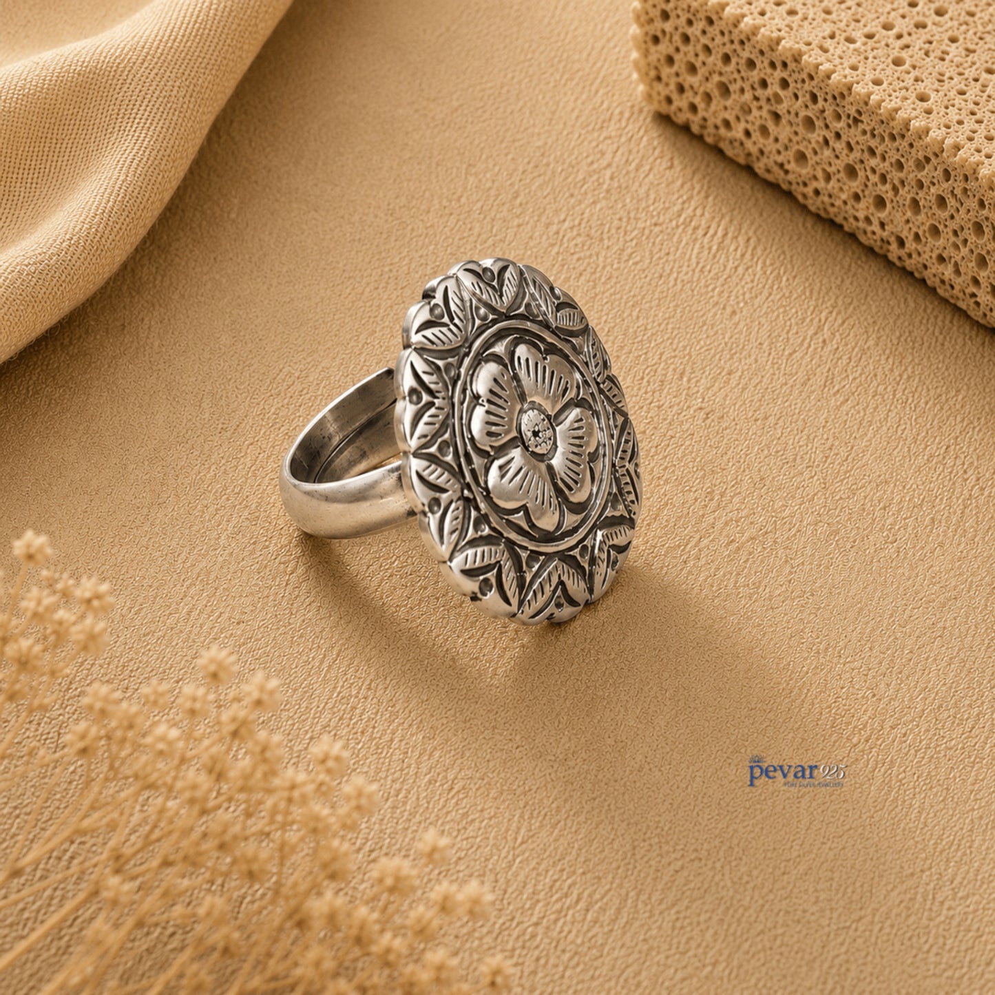 pevar925 oxidized silver adjustable ring with round floral chitai engraving on a textured beige background