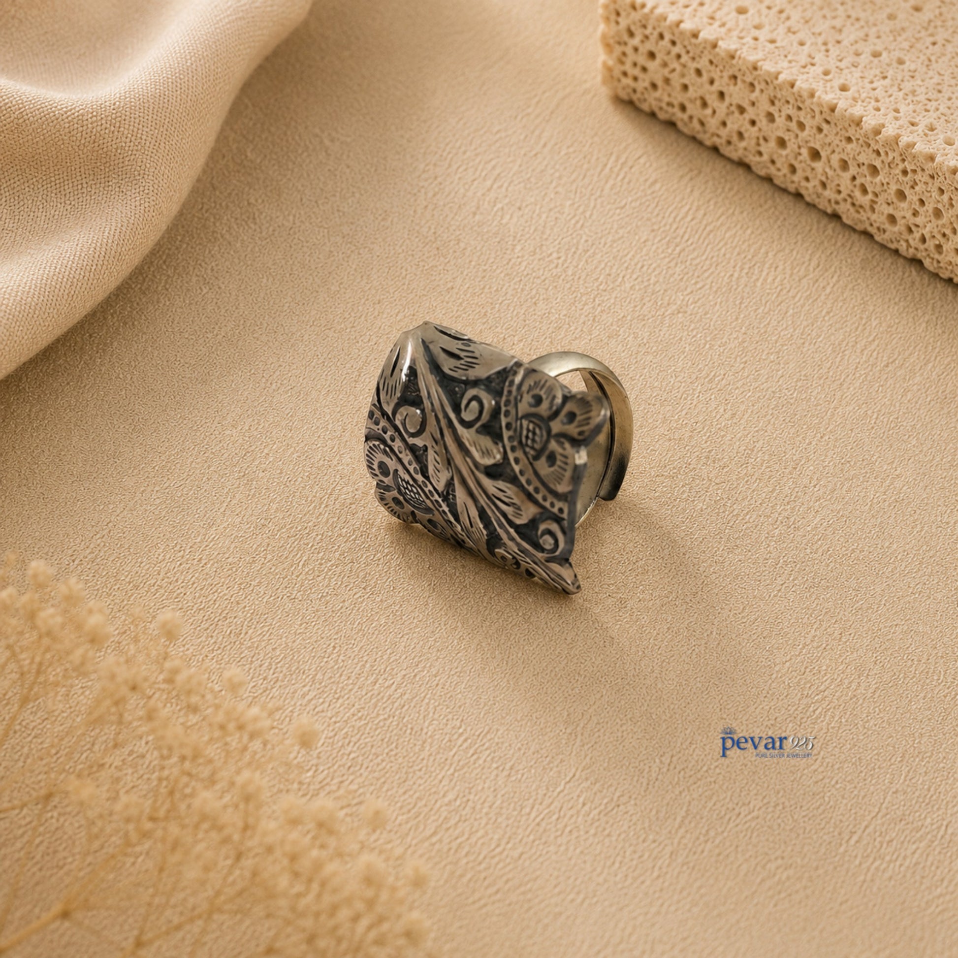 pevar925 oxidized silver adjustable ring with rectangular floral chitai engraving on a neutral textured background