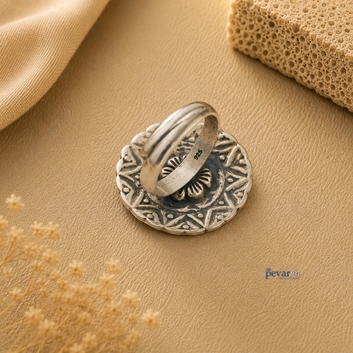 pevar925 oxidized silver adjustable ring with round floral chitai engraving and 925 hallmark on a beige background