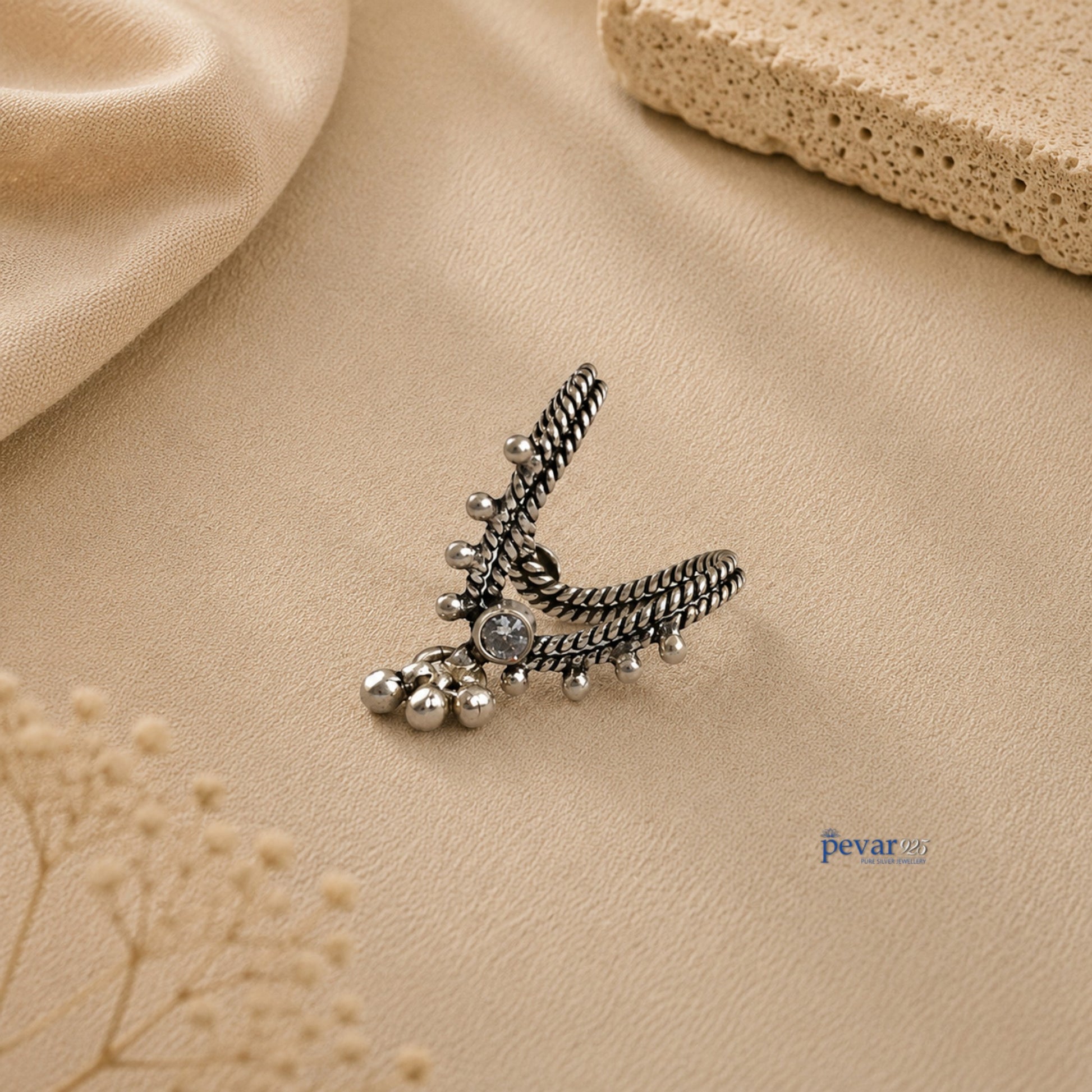 pevar925 oxidized silver V-shaped adjustable ring with central stone and dangling ghunghroo beads on beige background