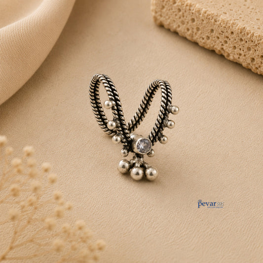 pevar925 oxidized silver V-shaped adjustable ring with central stone and dangling ghunghroo beads on a beige surface