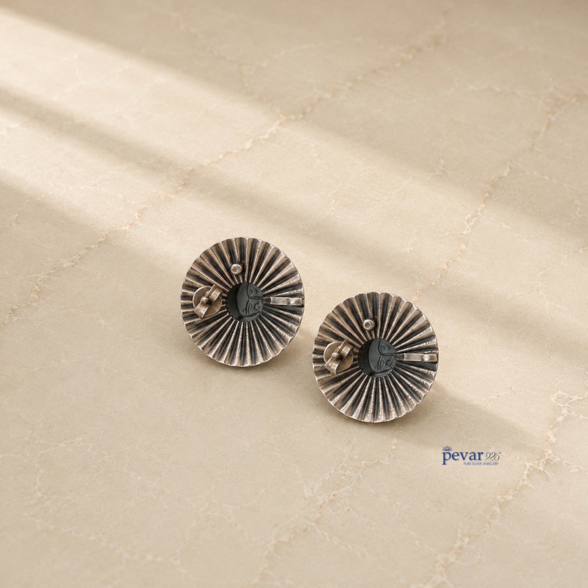 pevar925 oxidized silver temple goddess earrings with a circular ridged frame and golden motif on a neutral surface.