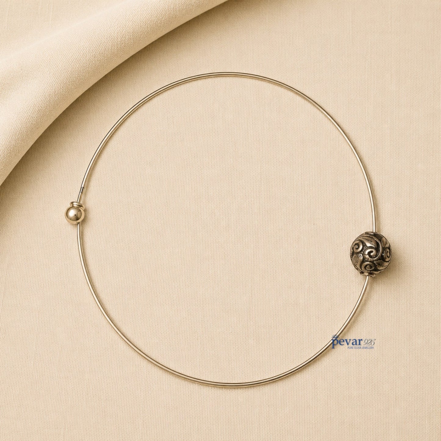 pevar925 oxidized silver hasli necklace with a central ornate bead featuring intricate swirl patterns on beige fabric