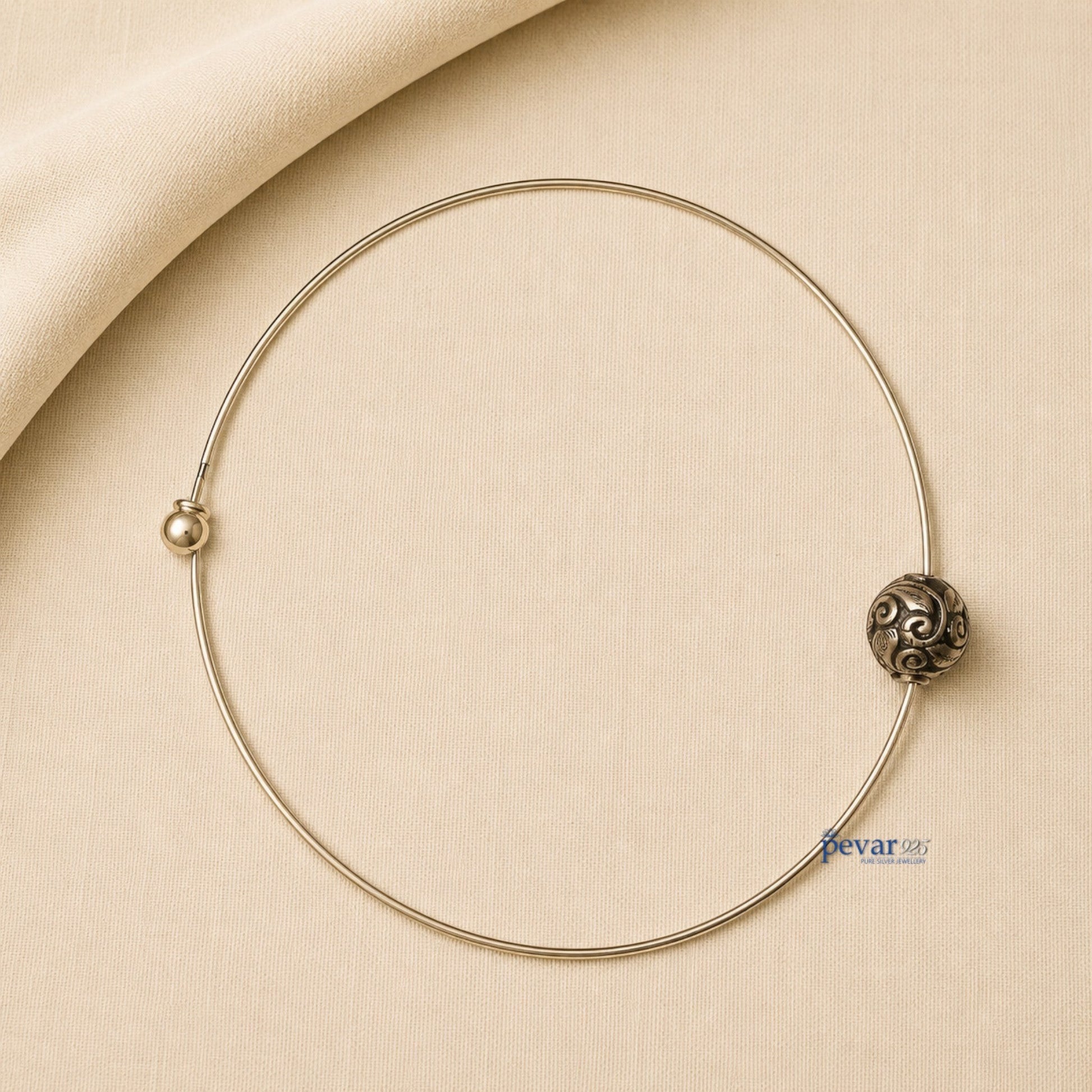 pevar925 oxidized silver hasli necklace with a central ornate bead featuring intricate swirl patterns on beige fabric