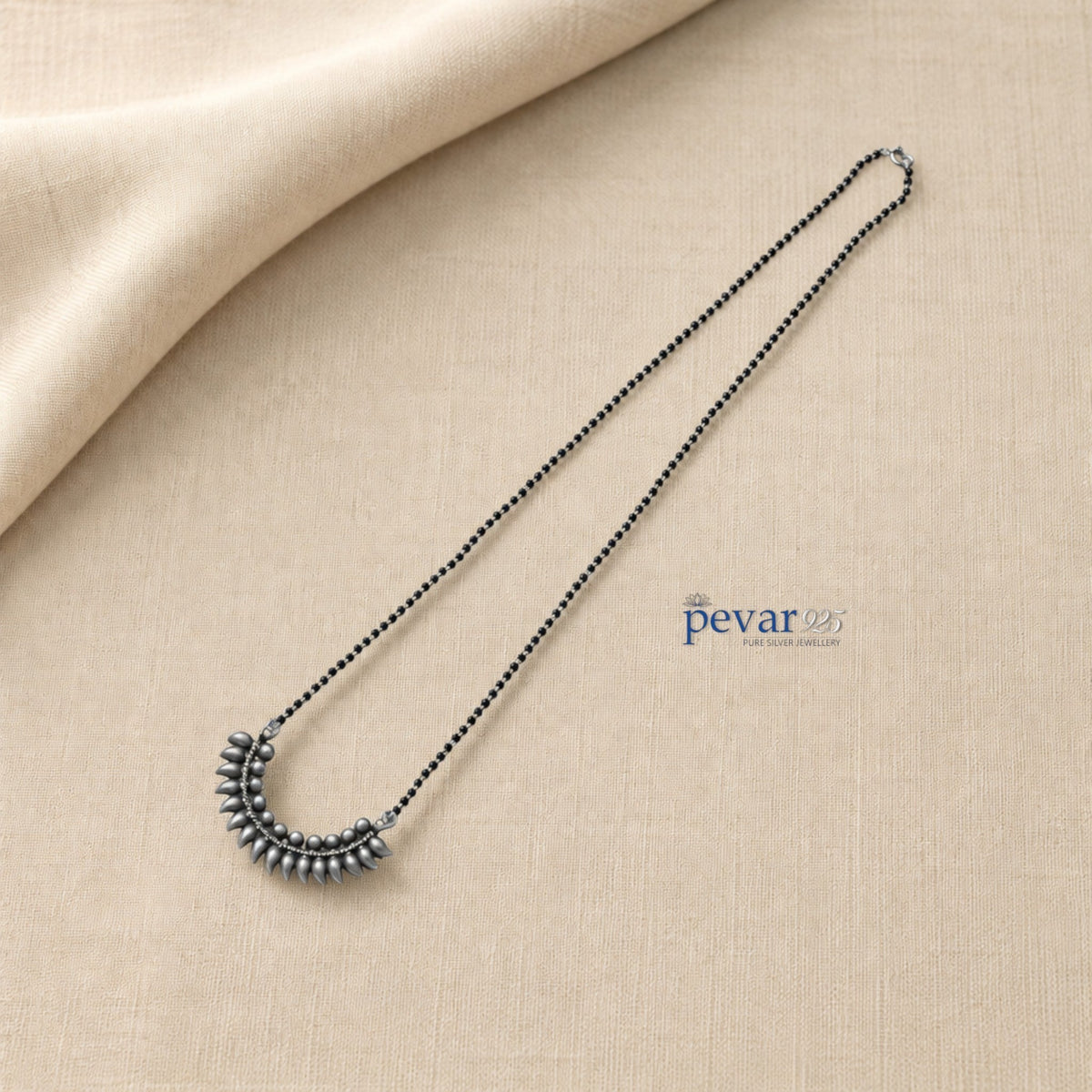 pevar925 oxidized 925 sterling silver mangalsutra with black beads and a crescent leaf motif pendant on beige fabric