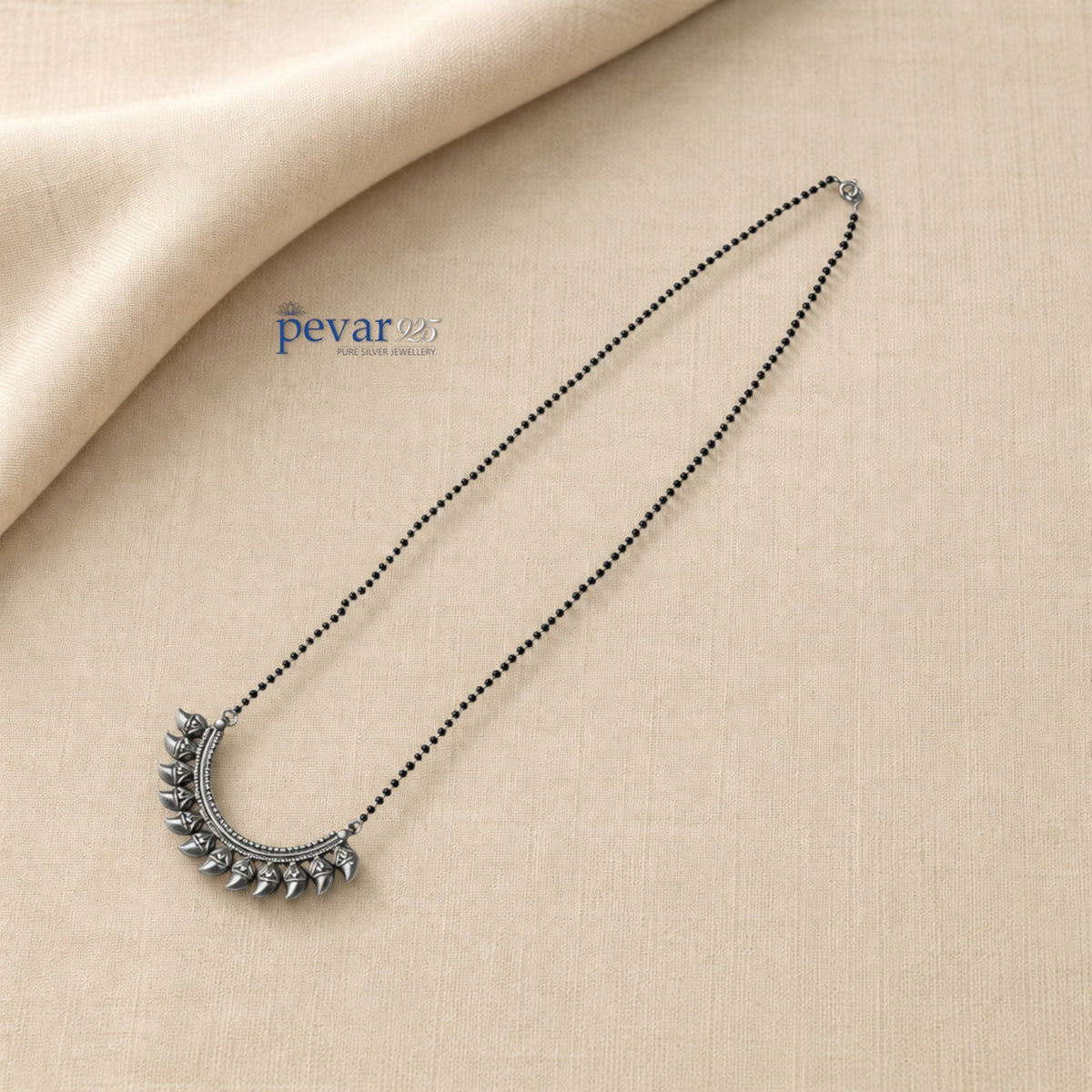 pevar925 oxidized 925 sterling silver mangalsutra with black beads and a crescent leaf pendant on beige fabric
