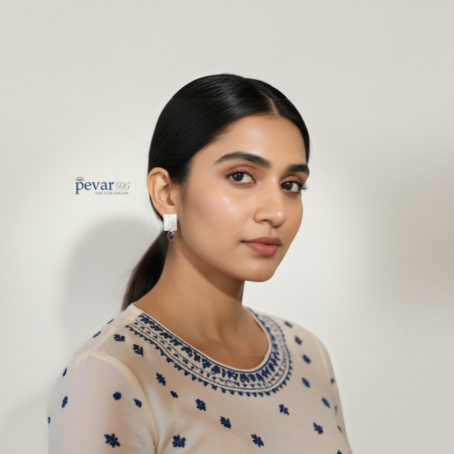 A model wearing pevar925 oxidized silver rectangular earrings with purple stones and intricate textured detailing.