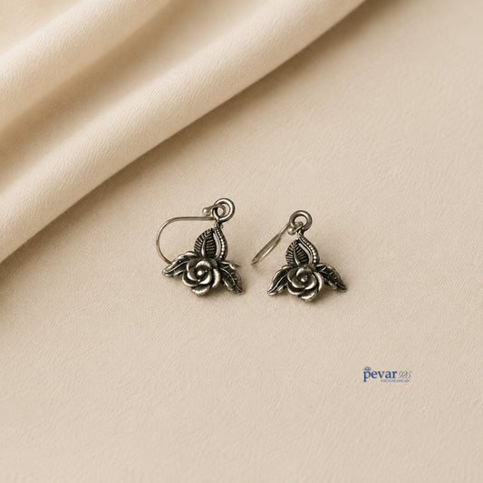 pevar925 oxidized silver rose petal earrings with intricate leaf detailing on a soft beige fabric background