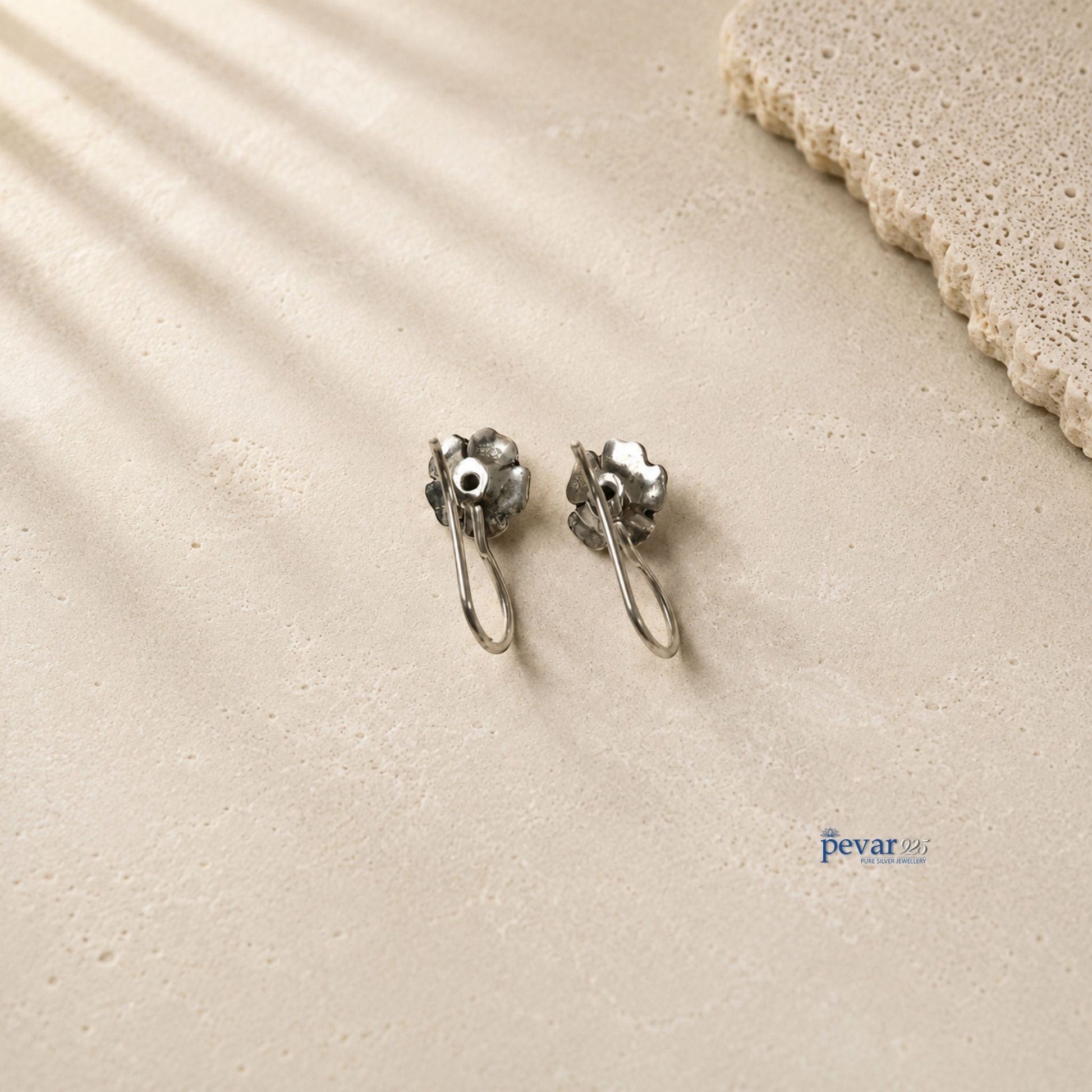 pevar925 oxidized 925 silver rose flower drop earrings with black stone accents on a textured beige surface