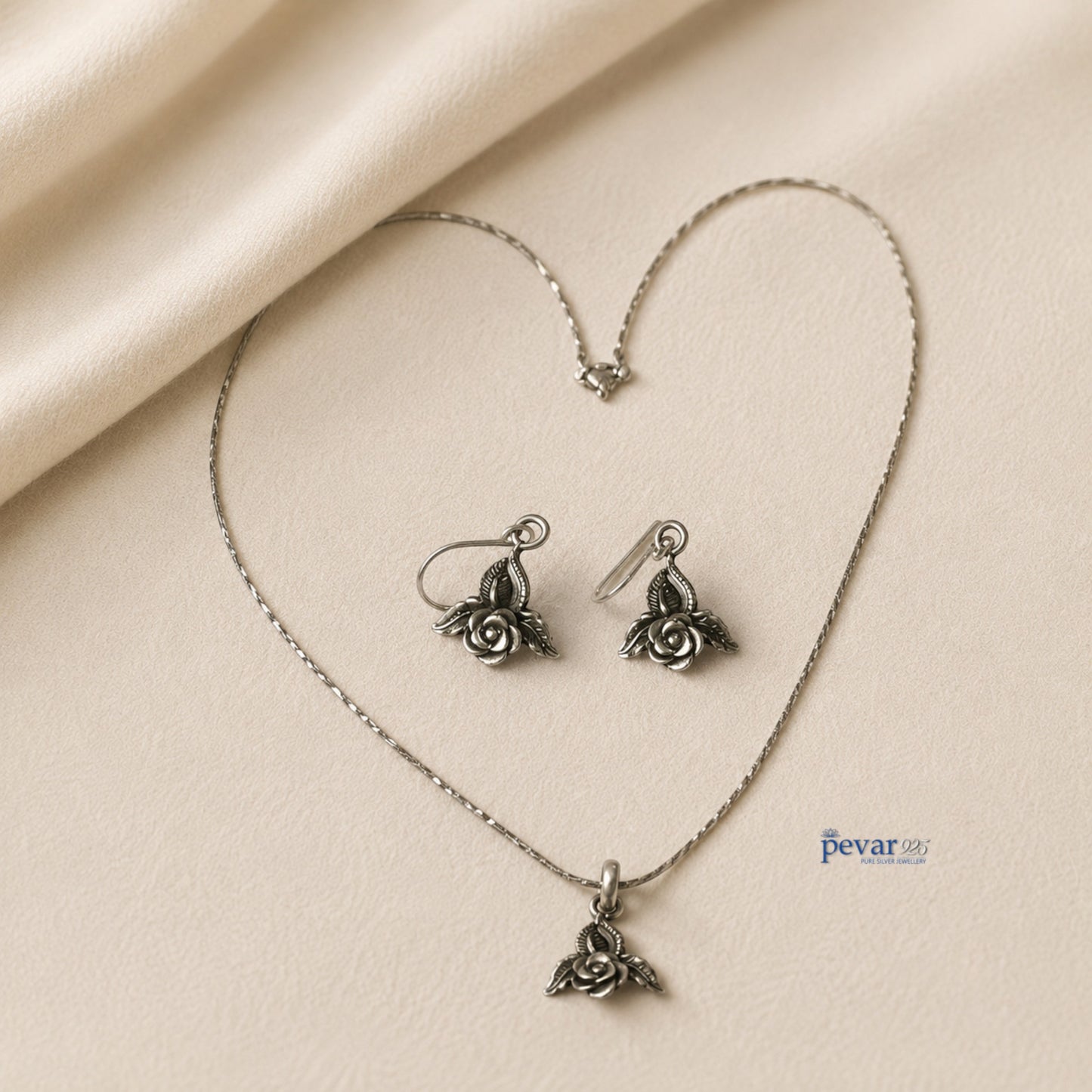 pevar925 oxidized silver rose petal pendant necklace and matching hook earrings on a soft beige fabric background