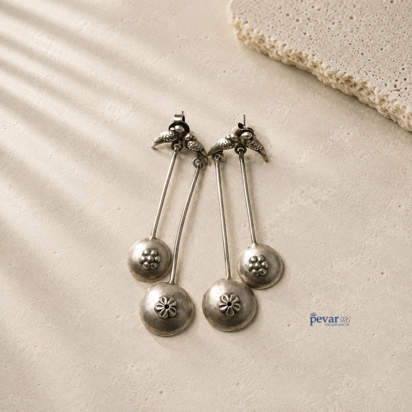 pevar925 oxidized 925 silver sparrow drop earrings with floral accents and antique finish on a textured stone surface