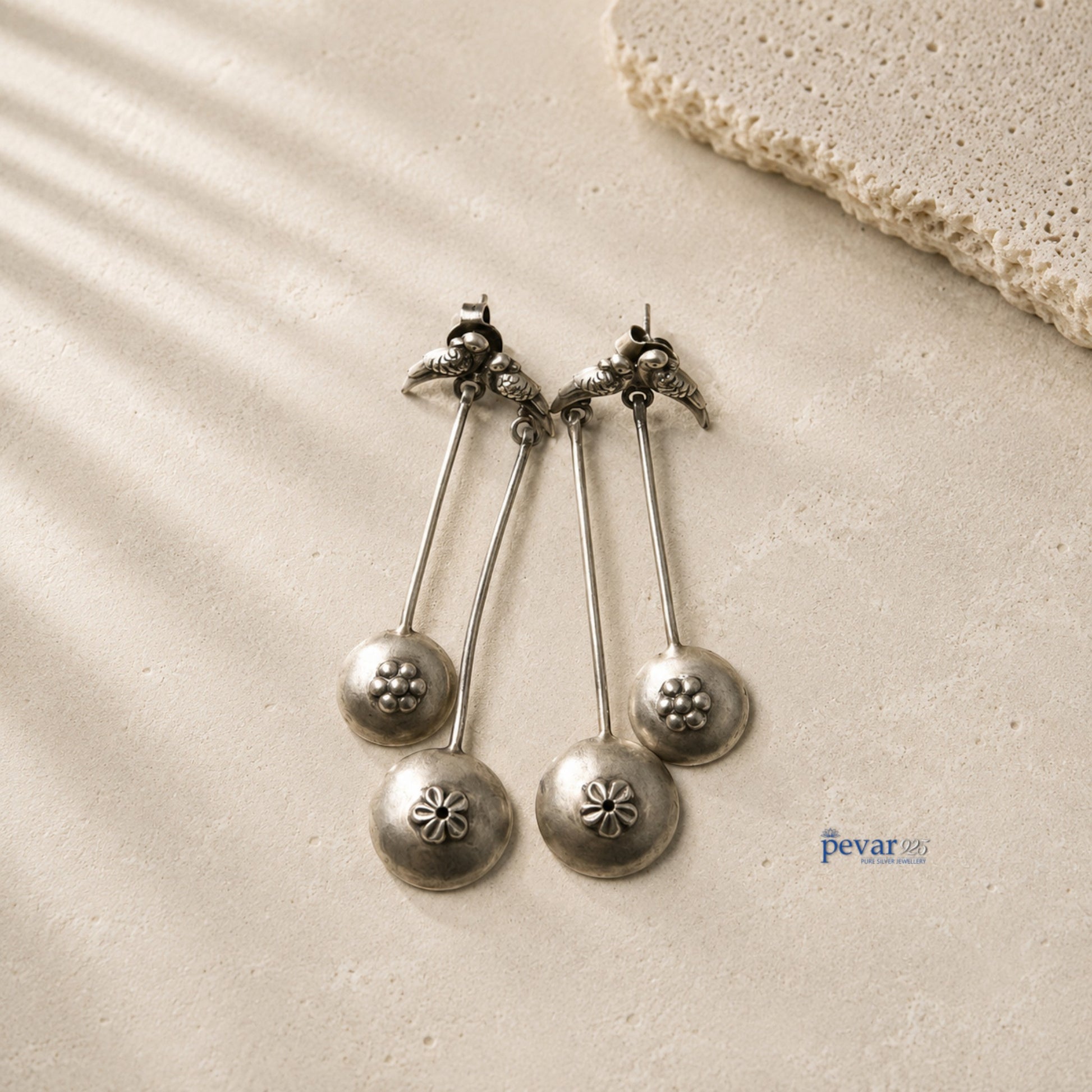 pevar925 oxidized 925 silver sparrow drop earrings with floral accents and antique finish on a textured stone surface