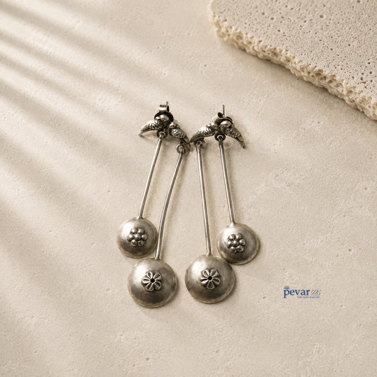 pevar925 oxidized 925 silver sparrow drop earrings with floral accents and antique finish on a textured stone surface