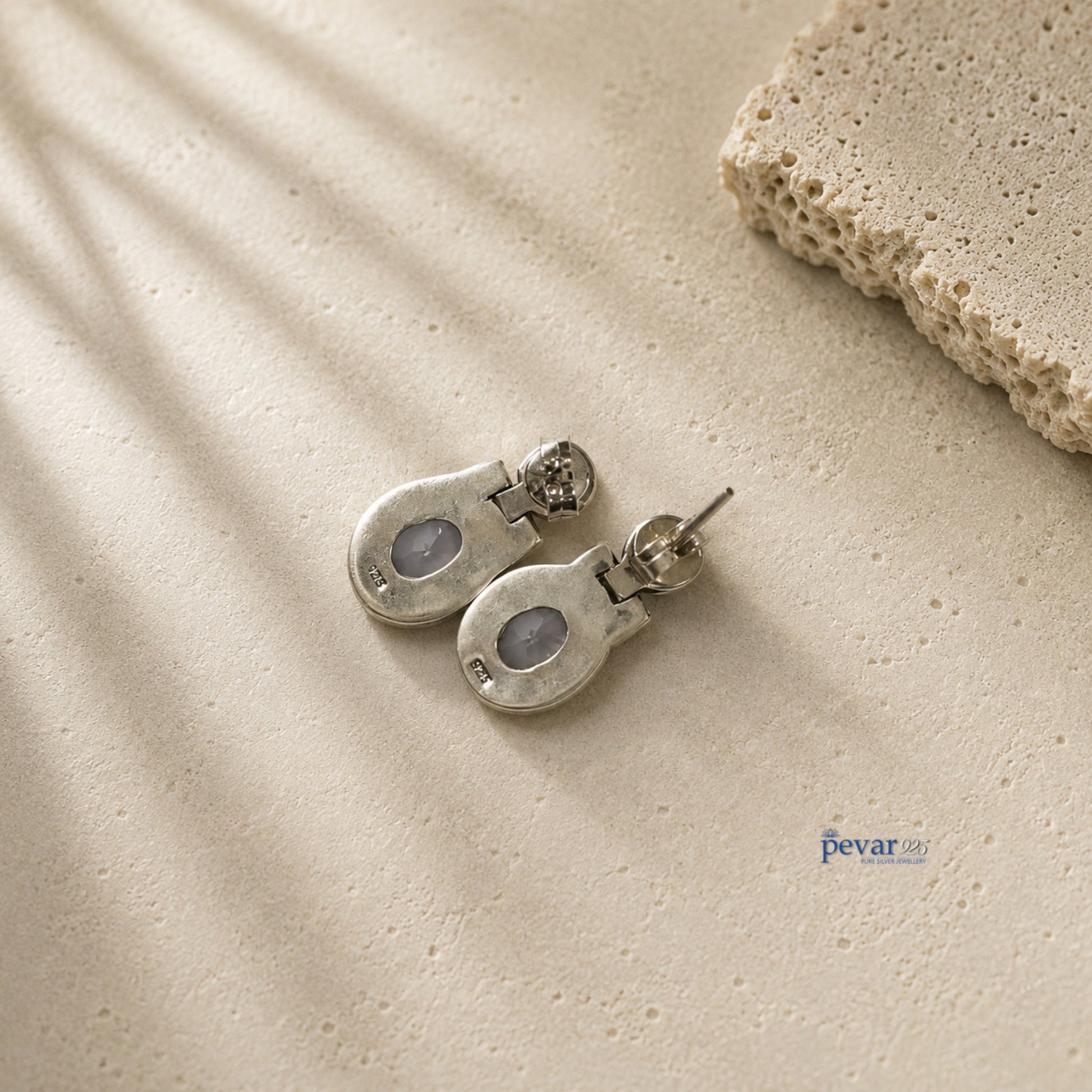 pevar925 oxidized 925 silver hook earrings with central shining stones on a textured beige surface