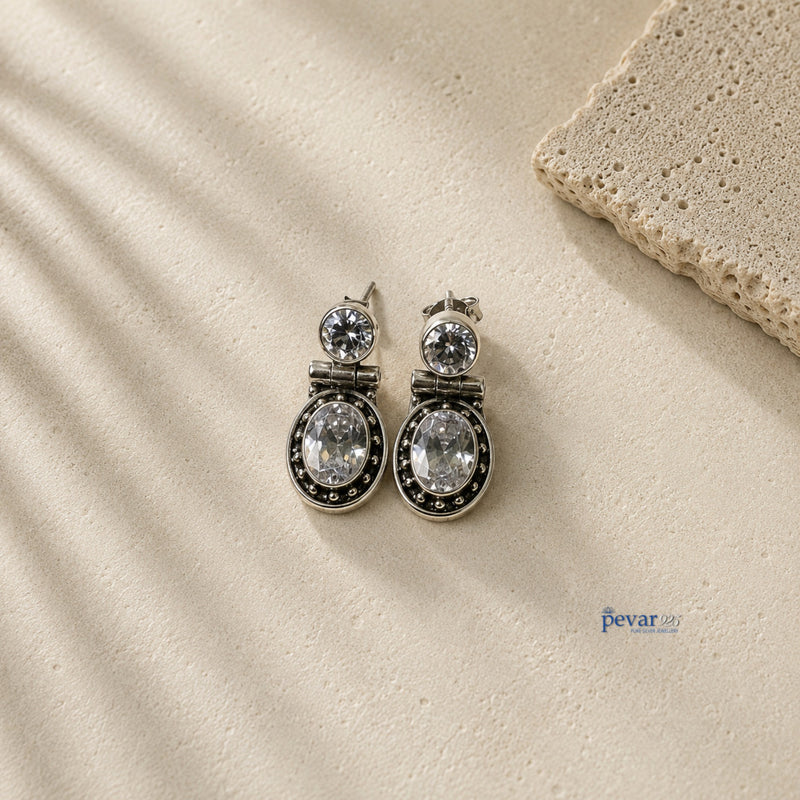 pevar925 oxidized 925 silver hook earrings featuring sparkling oval stones on a textured stone surface.