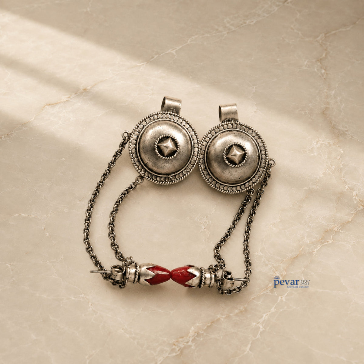 pevar925 oxidized 925 silver tribal earrings with intricate circular motifs and red stone accents on a marble surface